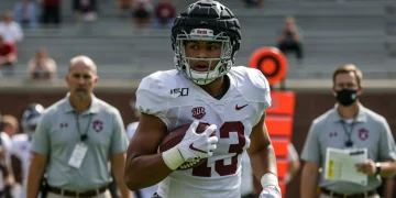 College football player wearing advanced helmet with medical staff on field