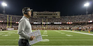 College football defensive coordinator analyzing game on sideline