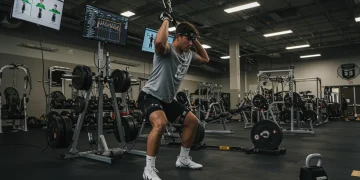 College football player training with advanced technology in a modern gym, showcasing strength and conditioning.